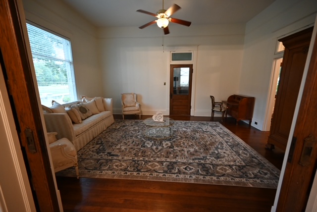 a living room with a rug and a ceiling fan