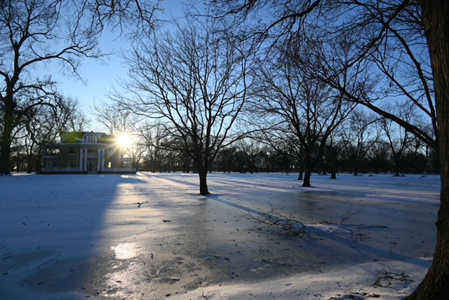 a snowy field with trees and a building